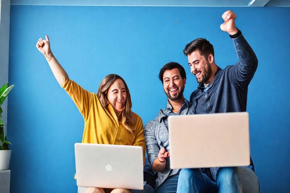 Empresários felizes celebrando o sucesso nas vendas online com a ajuda de estratégias de marketing digital.